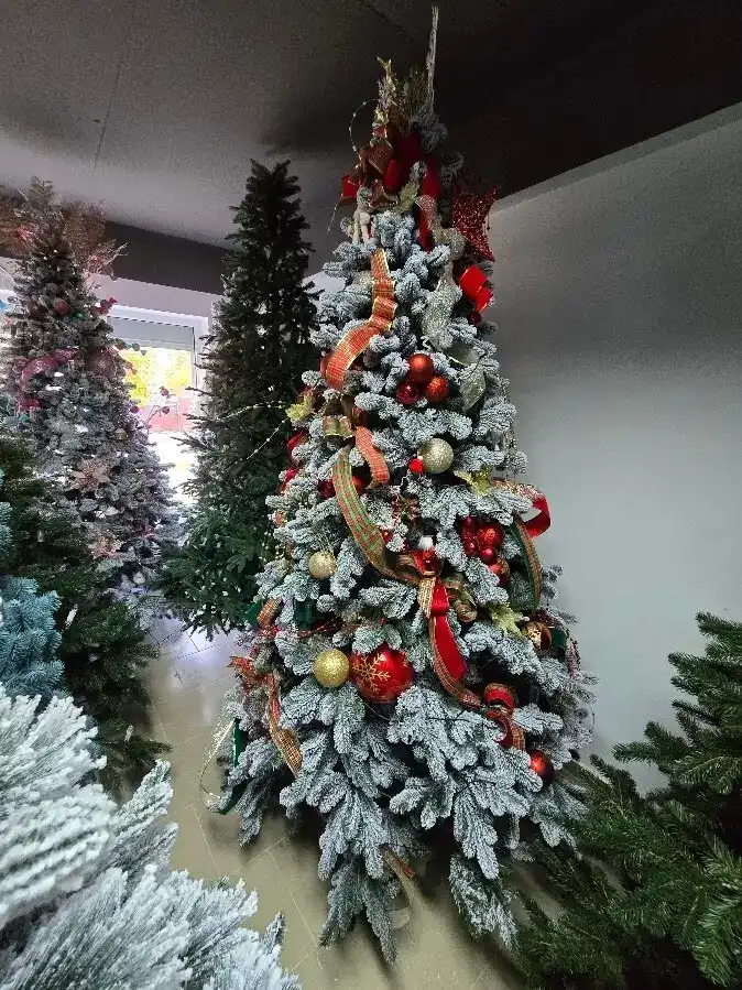 Brad artificial nins decorat în roșu și auriu, lângă alți brazi montați
