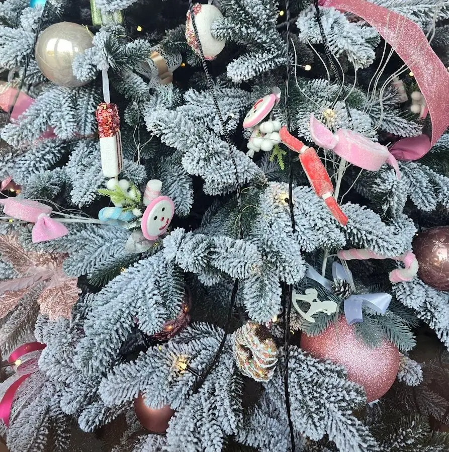 Brad artificial de Crăciun bogat, decorat cu globuri aurii și argintii, într-un living luminos.